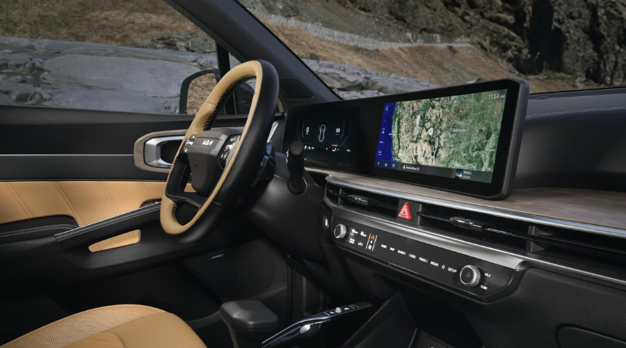 The high-tech 2026 Kia Sorento interior dashboard showcasing the twin panoramic curved digital display screens, two-tone leather steering wheel, and tactile physical climate controls. 