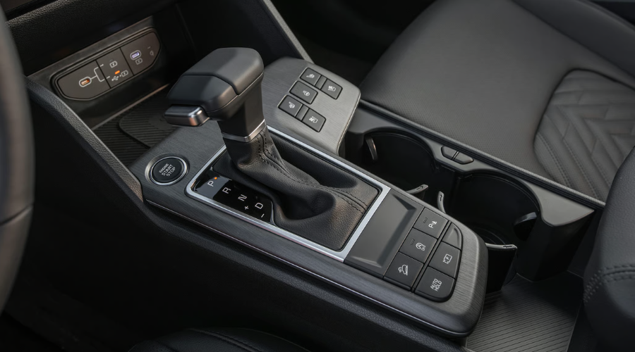 The sleek center console of a 2026 Kia Sportage featuring a geared eight-speed automatic transmission shifter and tactile physical buttons built for easy winter driving on Route 41 in Waukegan IL.