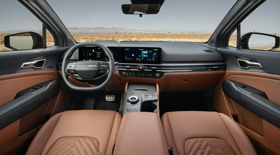Interior cabin view of the 2026 Kia Sportage featuring cognac brown leather seats, dual 12.3-inch panoramic display screens, multi-function steering wheel with Highway Driving Assist controls, and center rotary dial shifter available at Classic Kia near Waukegan, IL.