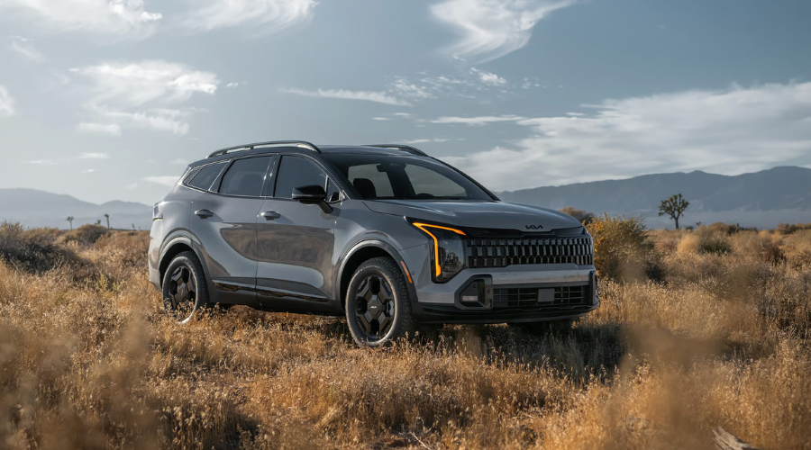 Front three-quarter exterior view of a gray 2026 Kia Sportage compact crossover highlighting its signature amber LED headlights, gloss-black front grille with emblem radar sensor housing, and roof rails at Classic Kia near Waukegan, IL.
