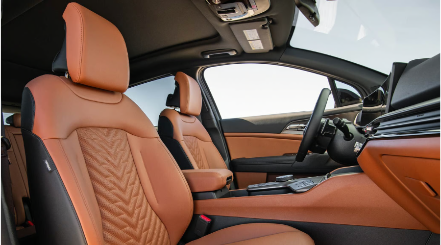 Side interior view of the 2026 Kia Sportage front cabin highlighting perforated cognac brown leather seats with chevron stitching, center console rotary shifter, and panoramic display housing available at Classic Kia near Waukegan, IL.
