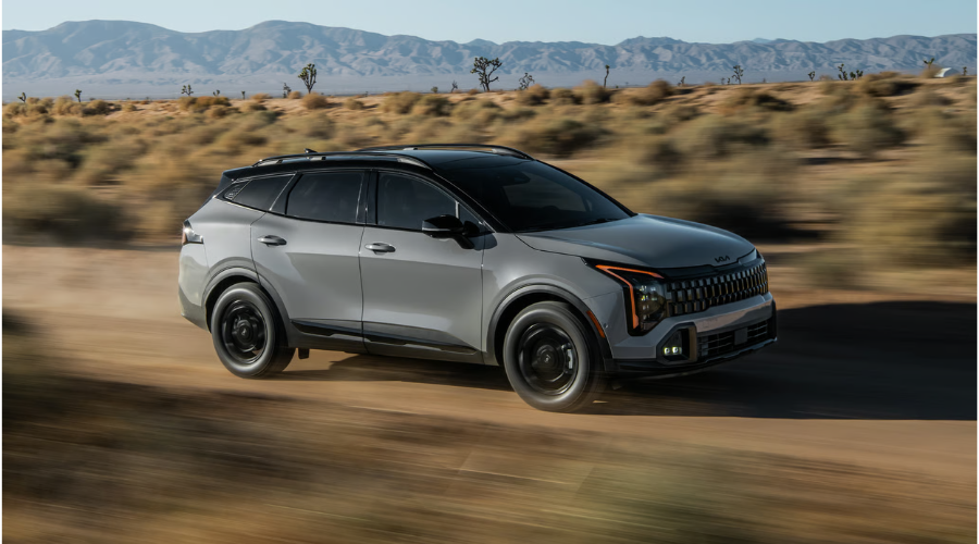 Dynamic action shot of a gray 2026 Kia Sportage crossover driving in motion, showcasing its two-tone black roof, amber LED daytime running lights, black wheels, and Drive Wise safety sensor suite available at Classic Kia near Waukegan, IL.