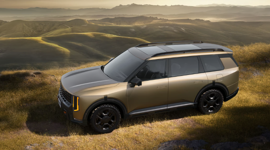 High-angle view of a bronze 2027 Kia Telluride X-Pro with black off-road wheels, all-terrain tires, and roof rails parked on a grassy ridge during autumn golden hour, representing the ideal 2026 Kia Telluride towing setup for fall camping trips across Waukegan, Gurnee, and Lake County IL.